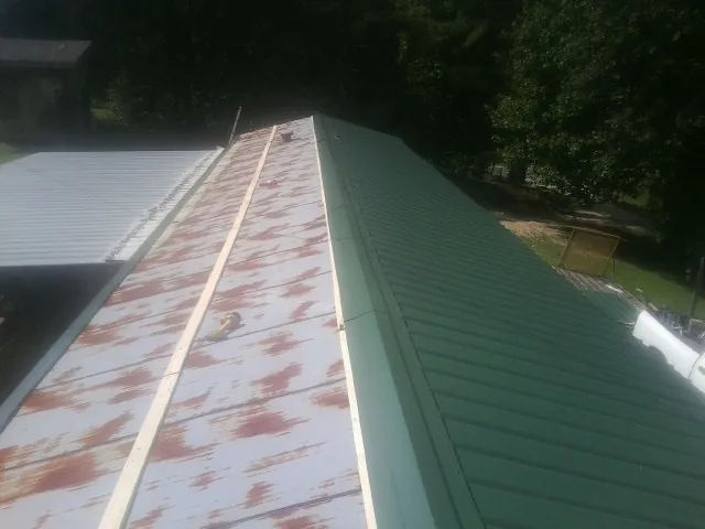 Old rusted panels beside newly installed green metal roofing — Wind Damage Roof Repair by Roofing Brothers in Juliustown