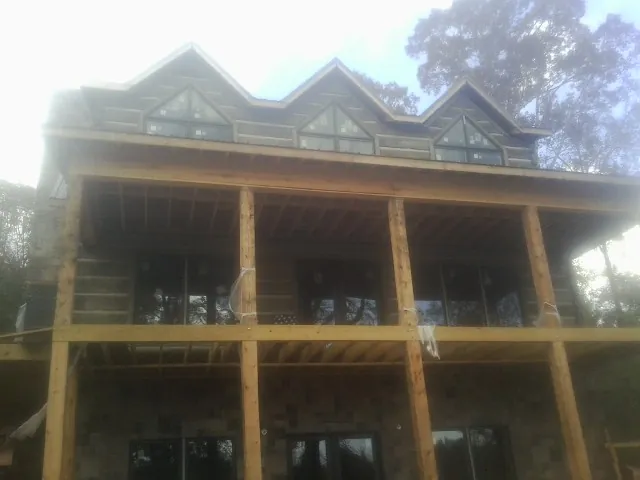 Dormers and porch framing on a large log home under construction — Roof Coating work by our crew in Juliustown
