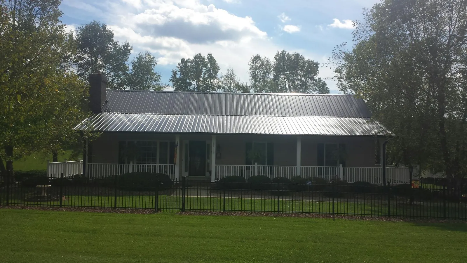 Gray metal roof on a brick ranch with a full width front porch — Gutter Guard Installation work by our crew in Juliustown