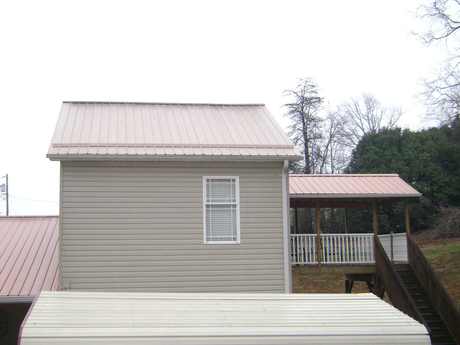 Tan metal roofs on a two story addition and attached porch, from a Roof Replacement job in Juliustown