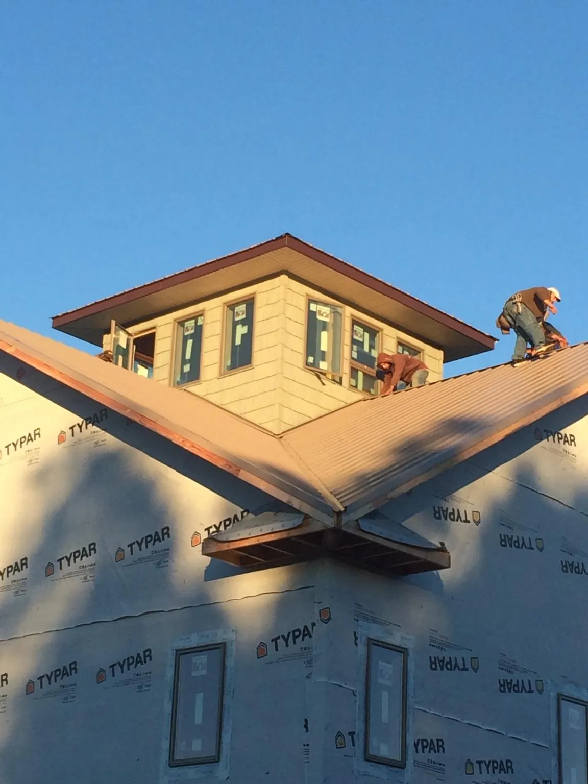 Roofers working around a rooftop cupola on a new metal roof at sunset — Roof Waterproofing in Juliustown by Roofing Brothers
